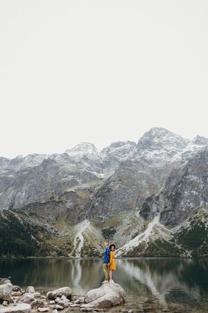 Lovely couple travelling together in the mountains, walking around the lake Morskie oko in Tatry. Amazing girl in yellow dress. Stunning view.の写真素材