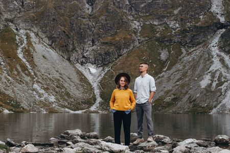 Lovely couple travelling together in the mountains, walking around the lake Morskie oko in Tatry. Amazing girl in yellow sweater. Stunning view.の写真素材