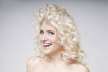 Beauty portrait of attractive young blonde woman with long hair. Looking at camera. Woman posing in the studio. Natural makeup. Background isolated on gray gradient. Surprise happy girl.の写真素材