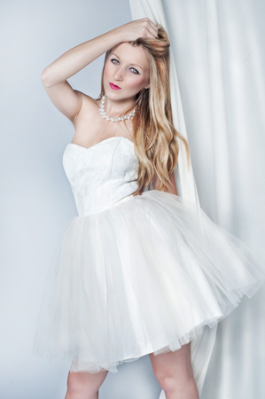 Beauty portrait of attractive young blonde woman with long hair. Looking at camera. Dance with white dressの写真素材
