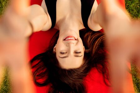 Pretty young woman smile to the camera lying on a sports matの写真素材