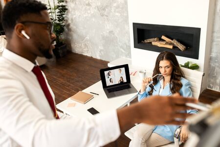 Photo of smiling young colleagues sitting in office coworking using laptop computers.