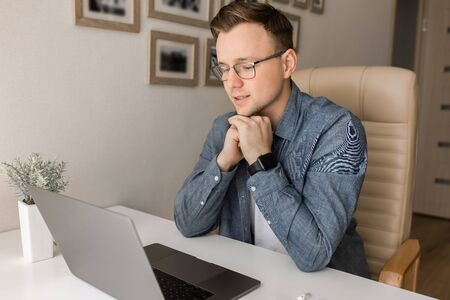 Young man working online at home or study using laptop at the table.