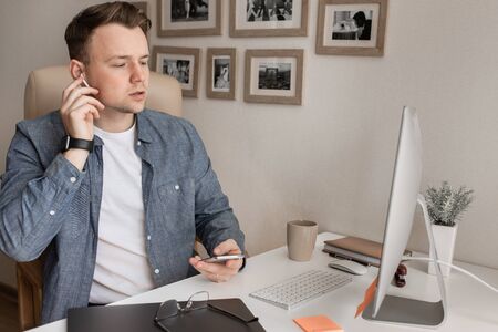 Young serious handsome white man working on a laptop from home using headphones.の写真素材