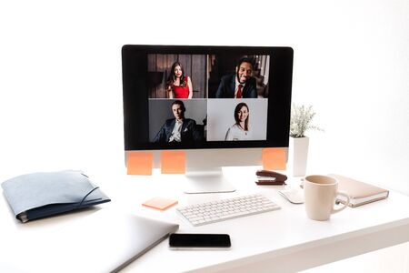 Monitor screen with video call and smartphone on a white office desktop. Top view.の写真素材