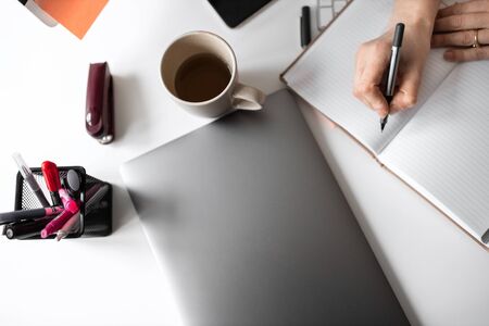 Office table with notepad, supplies, laptop, flower and coffee cup. Top view with copy spaceの写真素材