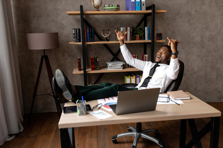 Smiling young african businessman relax while sitting at a table in the office. High quality photoの写真素材