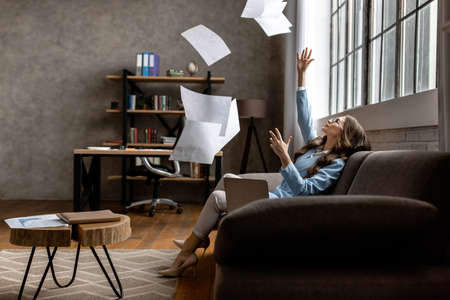 Serious business lady tired from work in the office throwing papers. High quality photo