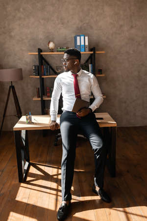 Portrait of handsome african business man with red tie and black glasses in the officeの写真素材