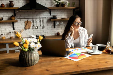 Attractive business woman working with laptop at the kitchen. Work from home concept. High quality photoの写真素材