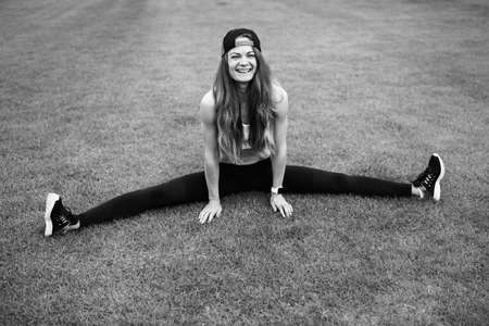 Overjoyed sporty woman doing stretching at the stadium, practice flexibility, smilie, doing daily...