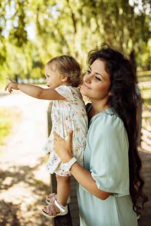 Portrait of gorgeous woman with lovely baby girl at the park, beautiful mother hold little daughter, smiling, enjoy happy moments together, motherhood and childhood concept. High quality photoの写真素材