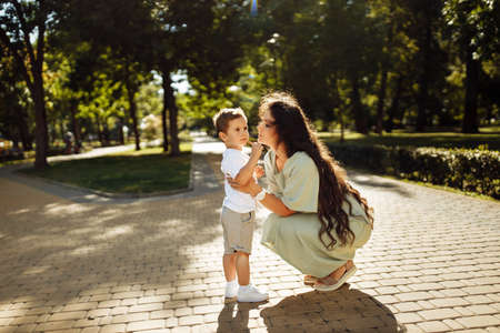 Lovely woman with little boy at the park, loving mother hugging with happy son, smiling, mom and toddler spend time together, enjoy tender family moments, parenting conceptの写真素材