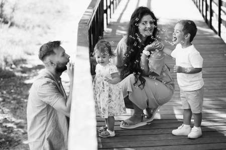 Happy son and adorable daughter with loving parents at the park, beautiful woman smiling, caring...