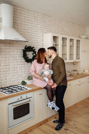 Beautiful young family with little daughter at the kitchen, decorate the house for Christmas celebration, happy parents with cute toddler spend winter holidays, xmas concept. High quality photoの写真素材