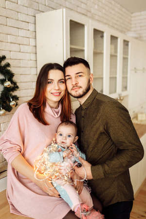Beautiful young family with little daughter at the kitchen, decorate the house for Christmas celebration, happy parents with cute toddler spend winter holidays, xmas concept. High quality photoの写真素材