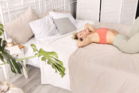 Blonde-hair beautiful girl waking up in a good mood, stretching. Sportive young woman relaxing after...