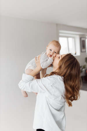 Joyful mother lift her adorable little daughter in the air, playing together. Beautiful woman with cute toddler smiling, having fun, happy motherhood and childhood concept. High quality photoの写真素材