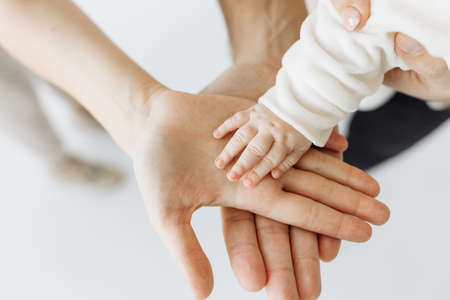 Close-up photo of hands. Family photo session with a little child, in the studio on a white background. The family expresses support and love for each other. High quality photoの写真素材