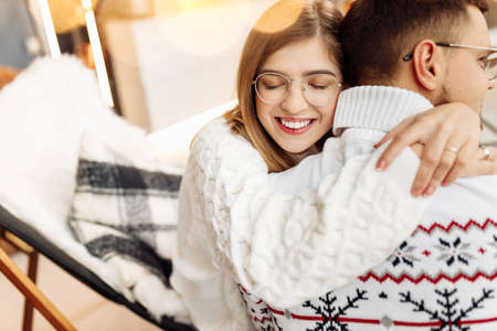 Lovely couple sitting at home, smiling, adorable woman hug charming man, happy husband spend cozy winter holidays with beautiful wife, festive mood, Christmas concept. High quality photoの写真素材