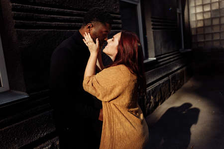 Portrait of wonderful couple cuddling near the house at the city, charming husband gently hug adorable wife, overjoyed woman smiling, spend time together, street photoshoot concept. High quality photoの写真素材