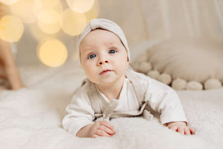 Portrait of adorable baby girl laying on comfortable canopy bed at home, beautiful cute toddler look at the camera with big interest, childhood and childcare concept. High quality photoの写真素材