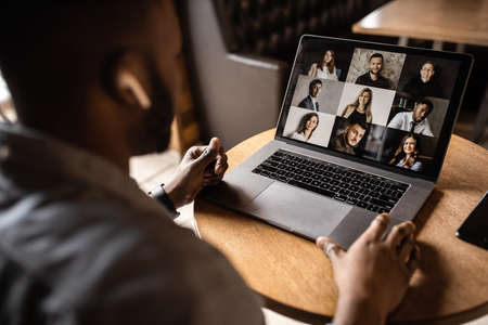 Young African American businessman looks into the laptop screen, speaks by video communication with his colleagues. Business entrepreneur, sitting in an office, pondering a business plan.の写真素材