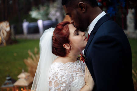 Portrait of lovely couple on wedding ceremony, handsome African American man with adorable white woman cuddle near decorated arch, enjoy happy unrepeatable moment, marriage concept. High quality photoの写真素材