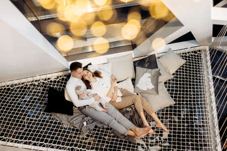 Beautiful parents with adorable baby girl laying at home, smiling, young family with little daughter enjoy happy moments, cozy winter holidays, motherhood and fatherhood concept. High quality photoの写真素材