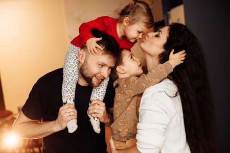 Portrait of overjoyed parents with little kids at home, smiling and cuddling. Happy family with adorable daughter and joyful son spend time together. Fatherhood and motherhood conceptの写真素材