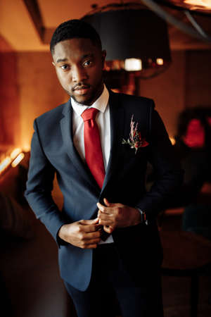 Portrait of handsome African American groom. Attractive charming man look at the camera, smiling, excited about marriage. Young adult business male wearing stylish formal suit. High quality photoの写真素材