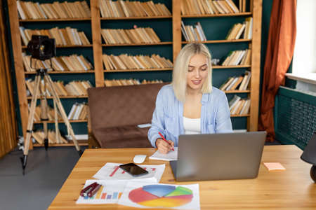 Happy female freelancer or student is using laptop, having a video meeting or webinar training,...