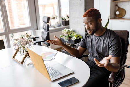 Happy male freelancer using laptop, having a video meeting with coworkers, smiling. Successful businessman discussing a project with colleagues at online conference, remotely work conceptの写真素材