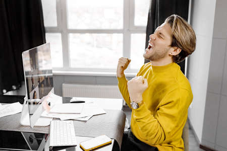 Joyful male freelancer having a video conference, hearing good news about his project, enjoying...