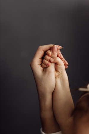 Close-up of baby daughter's hand holding mother's finger with tenderness on the dark background. Happy family moments of parents with their children. Love, family, maternity concept. High quality photoの写真素材