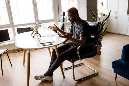 Concerned business man sit at workplace desk at home office cozy room working on laptop, make analysis sales stats results, learn graphs and holding online conference. Busy workday concept.の写真素材