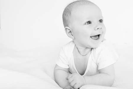Portrait of beautiful baby girl laying on comfortable bed at home, wonderful cute toddler look around with big interest, smiling, childhood and childcare concept. High quality photoの写真素材