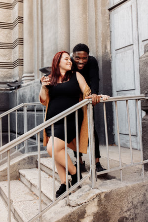 Wonderful couple cuddling near the house, walking at the city, charming husband gently hug adorable wife, overjoyed woman smiling, spend time together, street photoshoot concept. High quality photoの写真素材