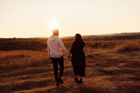 Wonderful couple walking at the field, attractive husband holding hands adorable wife, overjoyed woman smiling, happy family spend time together, weekends outdoors concept. High quality photoの写真素材