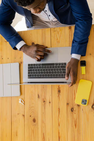 Top view of Afro American using laptop at the office desk, male hands of businessman, freelancer,...