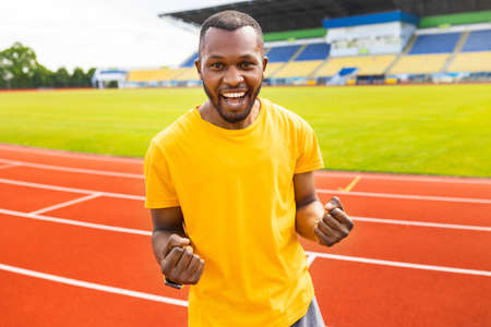 Emotional young afro american sportsman iin yellow trendy t-shirt celebrating victory, goal, success...