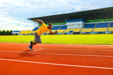 Attractive fit afro american man running fast along stadium during championship, black man doing...