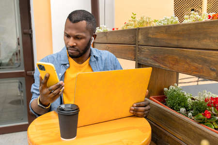 Busy pensive African American freelancer, student or businessman in casual clothing multitasking...