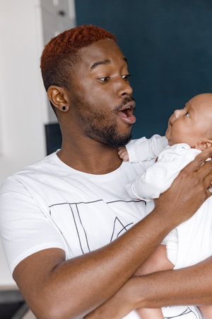 Happy young loving father holding newborn son child and laughing. Afro American caring father...