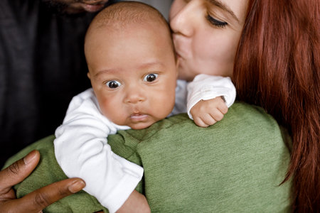 Close up of African American family mixed parents take care of cute baby at home. Caring young...