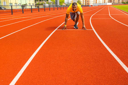 Fit focused afro-american male sportsman training hard and standing on starting position. Young...