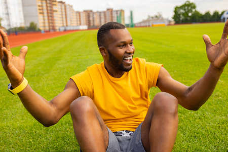 Young handsome sportsman african american man in yellow sport wear cheering carefree and excited at stadium field grass, celebrating victory. Victory concept. High quality photoの写真素材