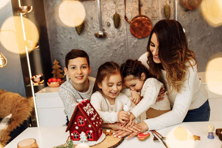 Joyful happy family baking cookies for Christmas dinner, lovely mother with son and two daughters having fun. Caring parent cooking with wonderful kids, smiling, spend winter holidays togetherの写真素材