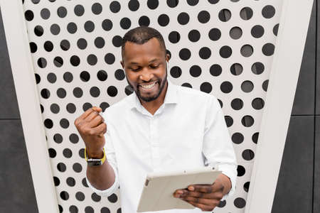 Happy male freelancer or student using tablet, received great news about job promotion or passed...