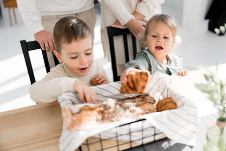 Beautiful little kids having a breakfast, sitting at the dining table at home. Joyful boy with cute...